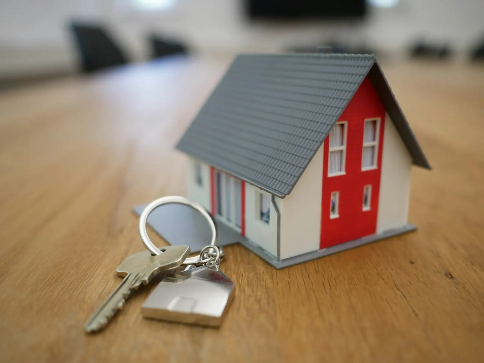 Small model house with a set of house keys on a wooden table