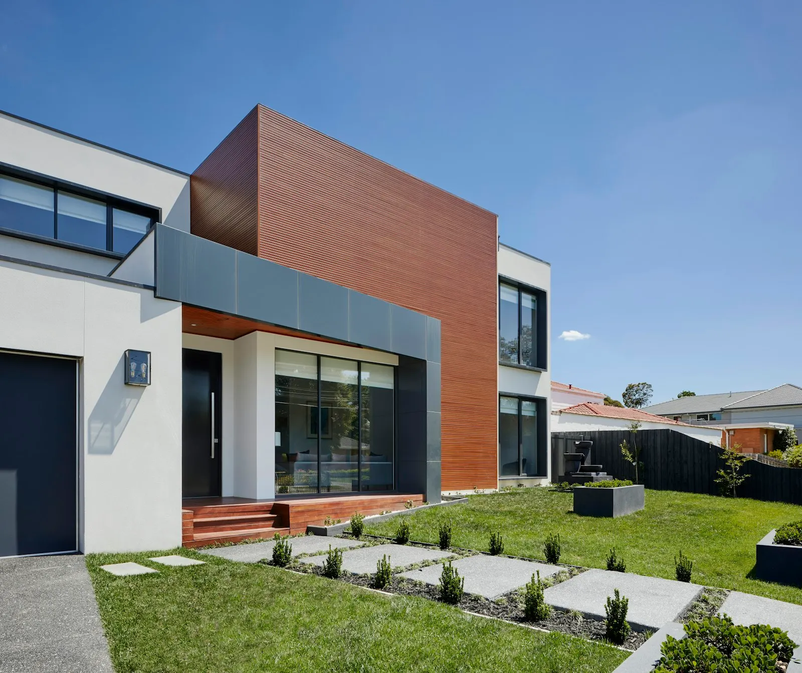 Contemporary white stucco home with wood accents and a landscaped front yard